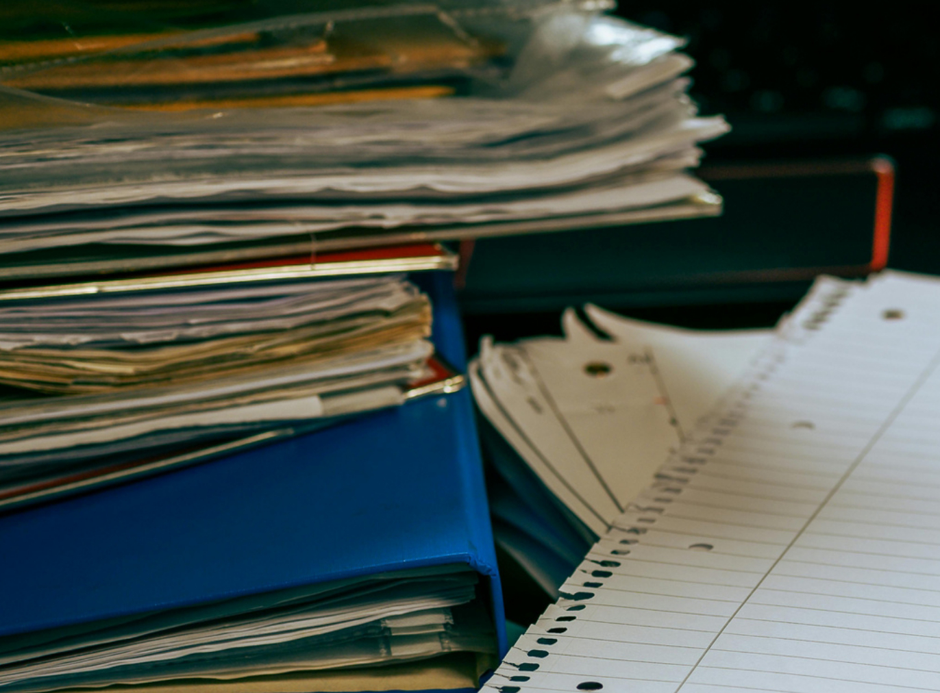 Stacked document folders and paper sheets representing Estate Administration paperwork